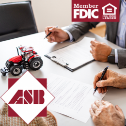 Farmer sitting at the bank with his local ag lender signing paperwork