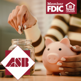 Woman's hand around a pink piggy bank with a clear jar of coins next to it