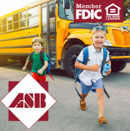 Two boys with backpacks on running by the school bus