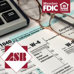 Stack of tax forms with reading glasses and edge of laptop on them