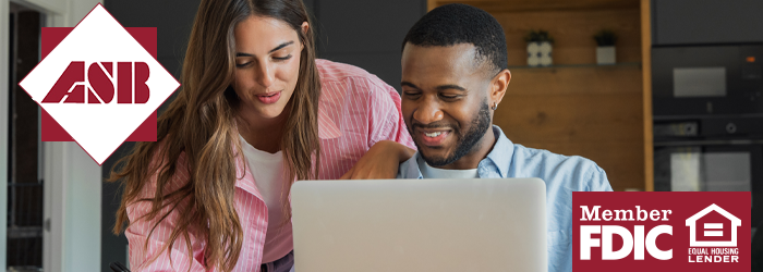 Man and Woman smiling looking at a computer