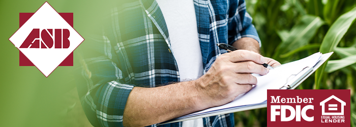 Farmer standing in the field writing on a clipboard