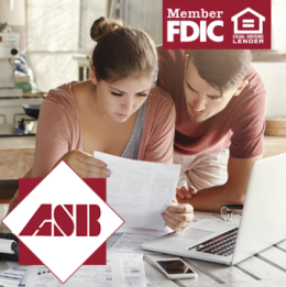 Couple reviewing financial paperwork together at the table in front of a laptop