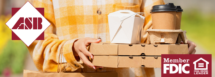Person walking outside with takeout boxes and takeout coffee