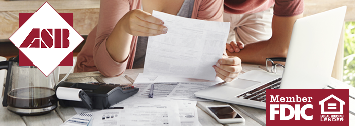 Couple reviewing financial paperwork together at the table in front of a laptop