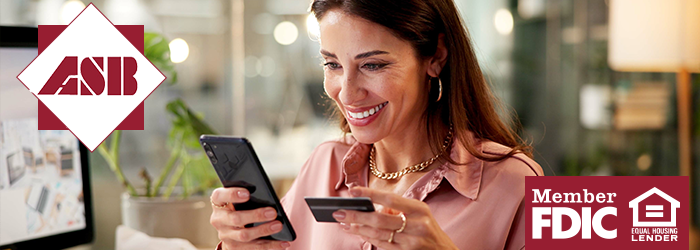 Woman smiling at her smartphone while holding her debit card in her other hand
